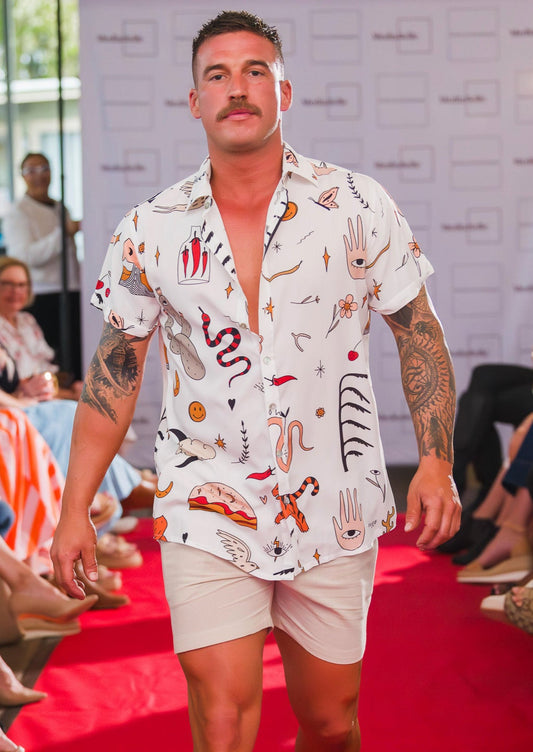 Model walking on a fashion show runway wearing our patterned greek boheme shirt and beige cotton shorts.